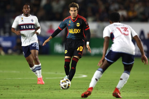 El mediocampista del LA Galaxy, Riqui Puig, centro, controla el balón contra...