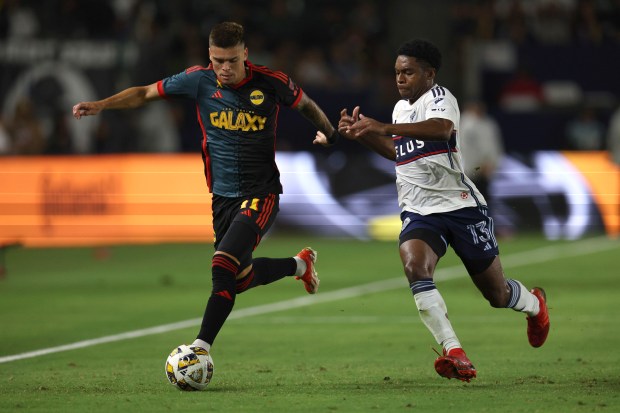 El delantero del LA Galaxy Gabriel Pec, izquierda, controla el balón contra...