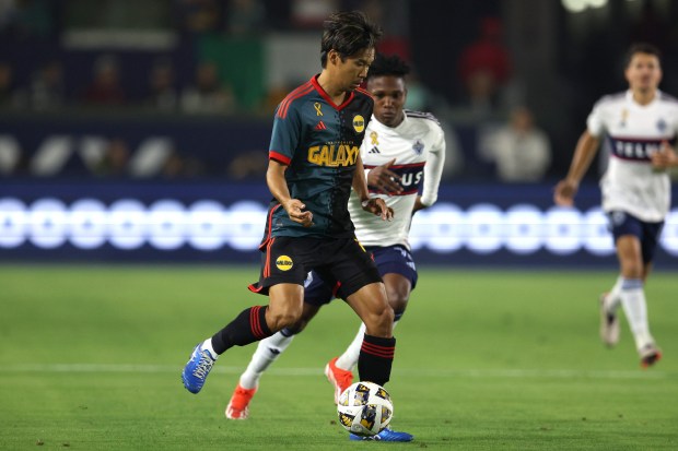 El defensa del LA Galaxy, Miki Yamane, al frente, mueve el balón contra...