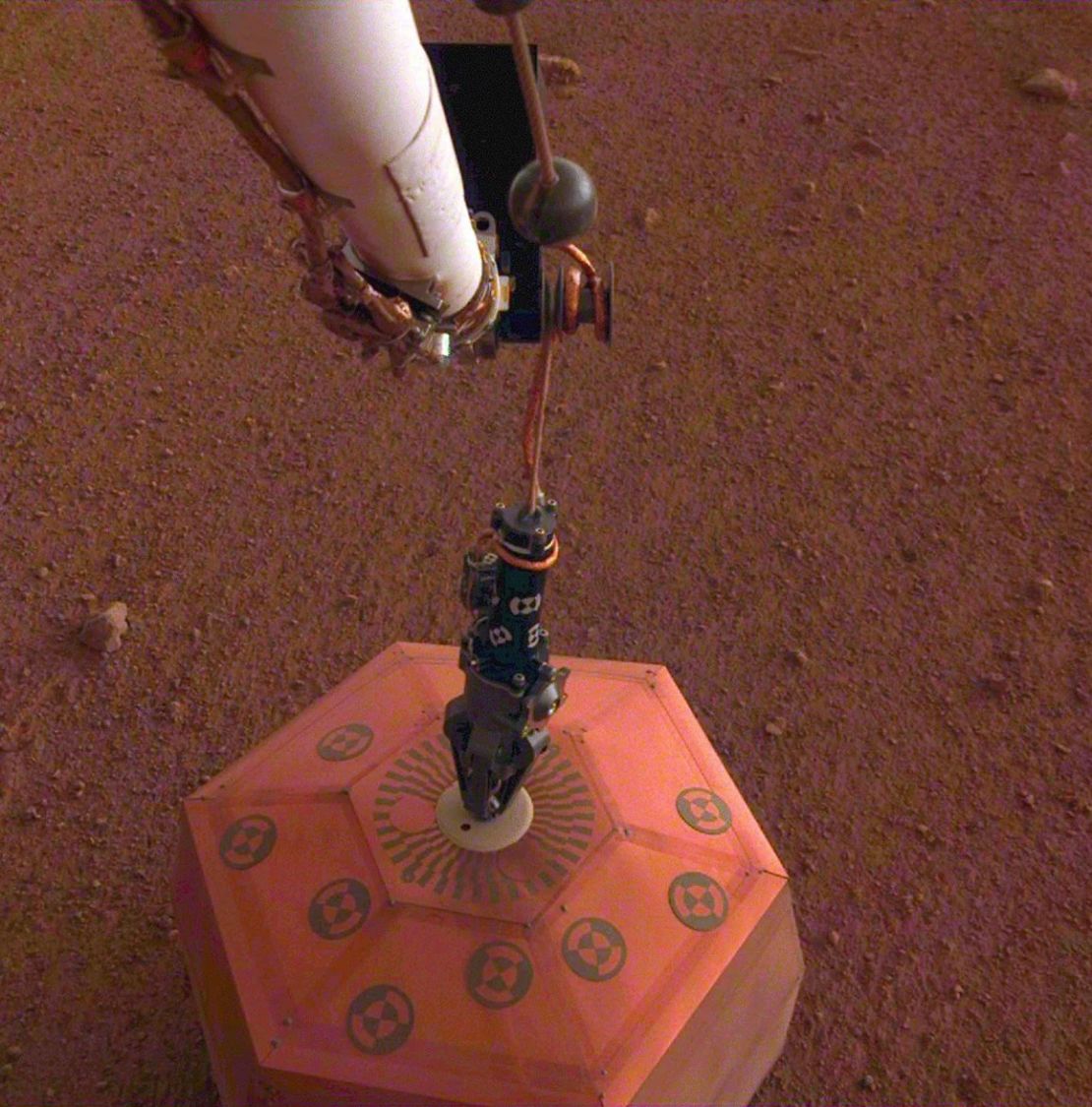 InSight's white robotic arm and black hand-shaped gripper deployed the first seismometer to another planet on December 19, 2018. Credit: NASA/JPL-Caltech.