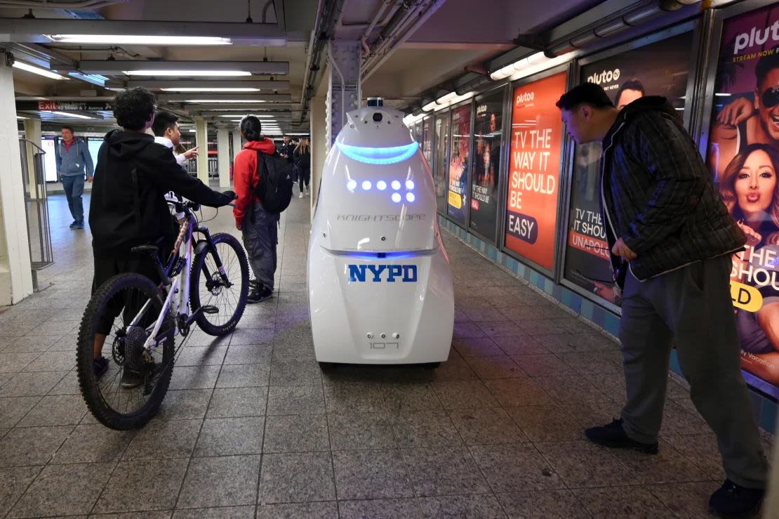 A group of travelers observe the NYPD's Knightscope K5 autonomous security robot at the Times Square subway station in New York.