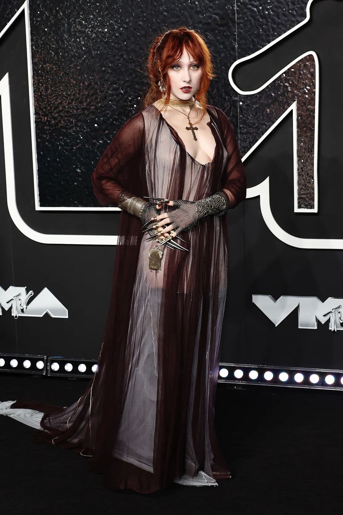 Chappell Roan paired her gothic-inspired Y/Project dress with a cross pendant and dramatic nails emerging from fingerless gloves. Credit: Jamie McCarthy/WireImage/Getty Images.