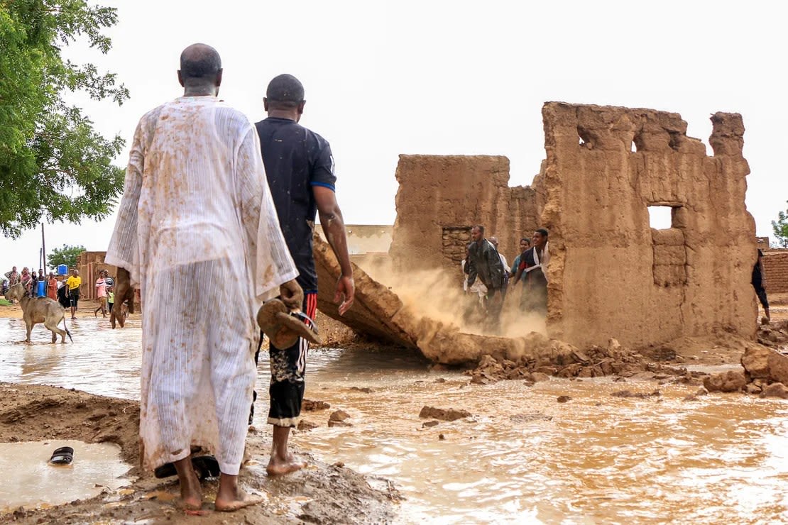 Men tear down the mud wall of a house to act as a makeshift dam amid flooding in the Messawi area, near Meroe, in the northern state of Sudan, on August 27, 2024.