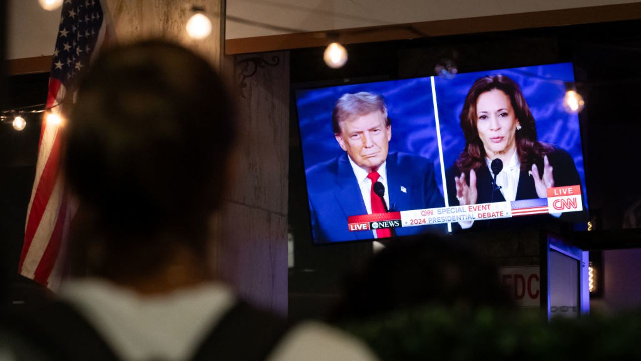 A walking past stops to watch a screen displaying the US Presidential debate between Vice President and Democratic presidential candidate Kamala Harris and former US President and Republican presidential candidate Donald Trump at The Admiral in Washington, DC, on September 10, 2024. (Photo by Allison Bailey / AFP) (Photo by ALLISON BAILEY/AFP via Getty Images)