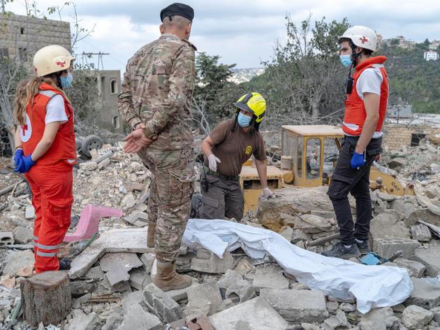 Los equipos de la Cruz Roja Libanesa y de defensa civil buscan entre los escombros partes de cuerpos, en un sitio dañado por un ataque aéreo israelí, en Aitou, Líbano, el 15 de octubre de 2024.