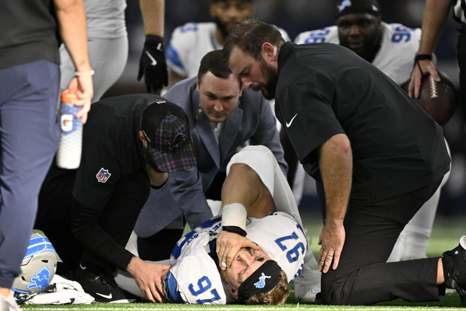 El ala defensiva de los Detroit Lions, Aidan Hutchinson (97), es atendido por el personal del equipo después de sufrir una lesión desconocida en la segunda mitad de un partido de fútbol americano de la NFL contra los Dallas Cowboys en Arlington, Texas, el domingo 13 de octubre de 2024. (Foto AP/Jerome Miron )